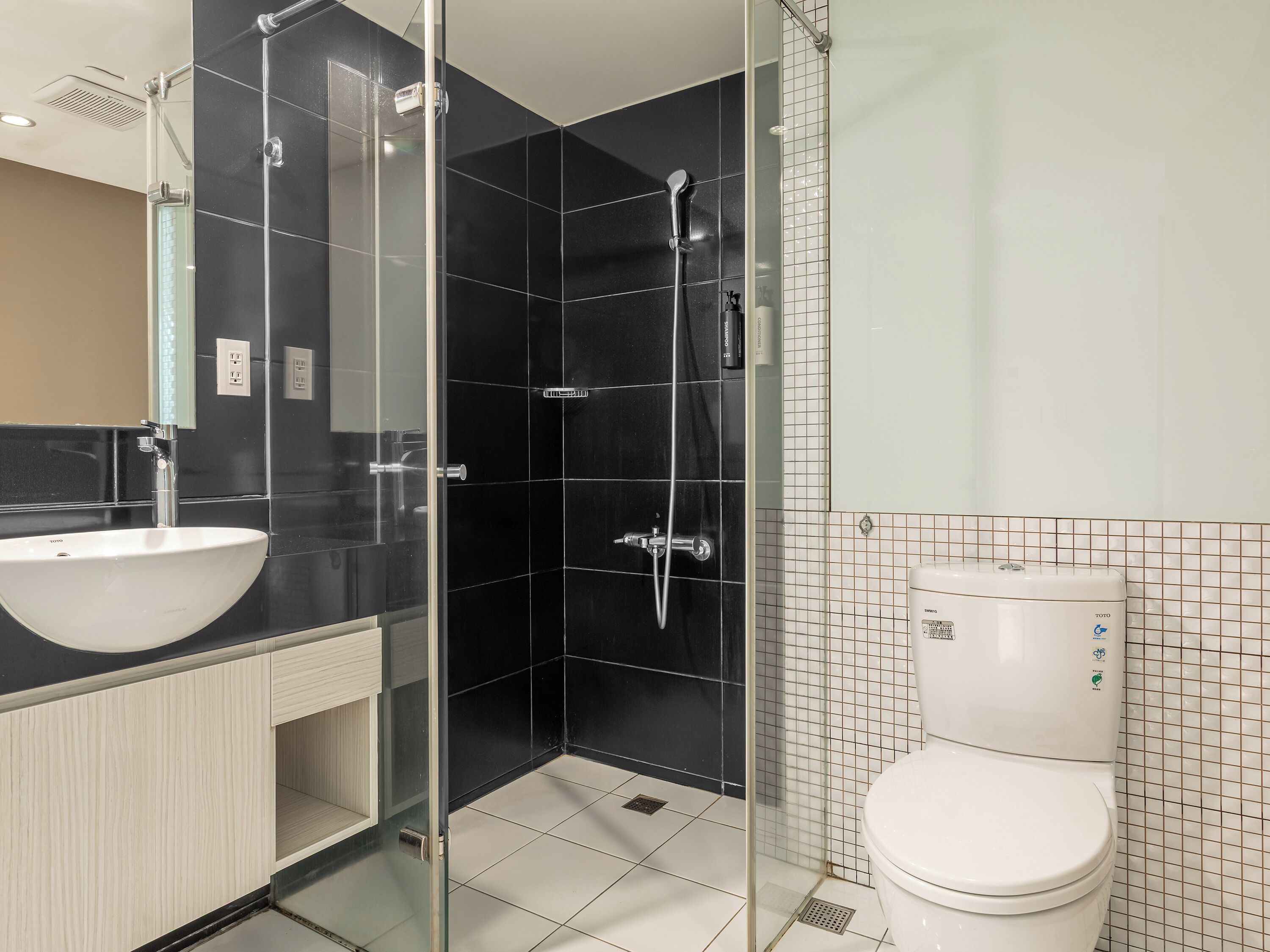 A modern bathroom with a glass-enclosed shower, a white sink, and a toilet.