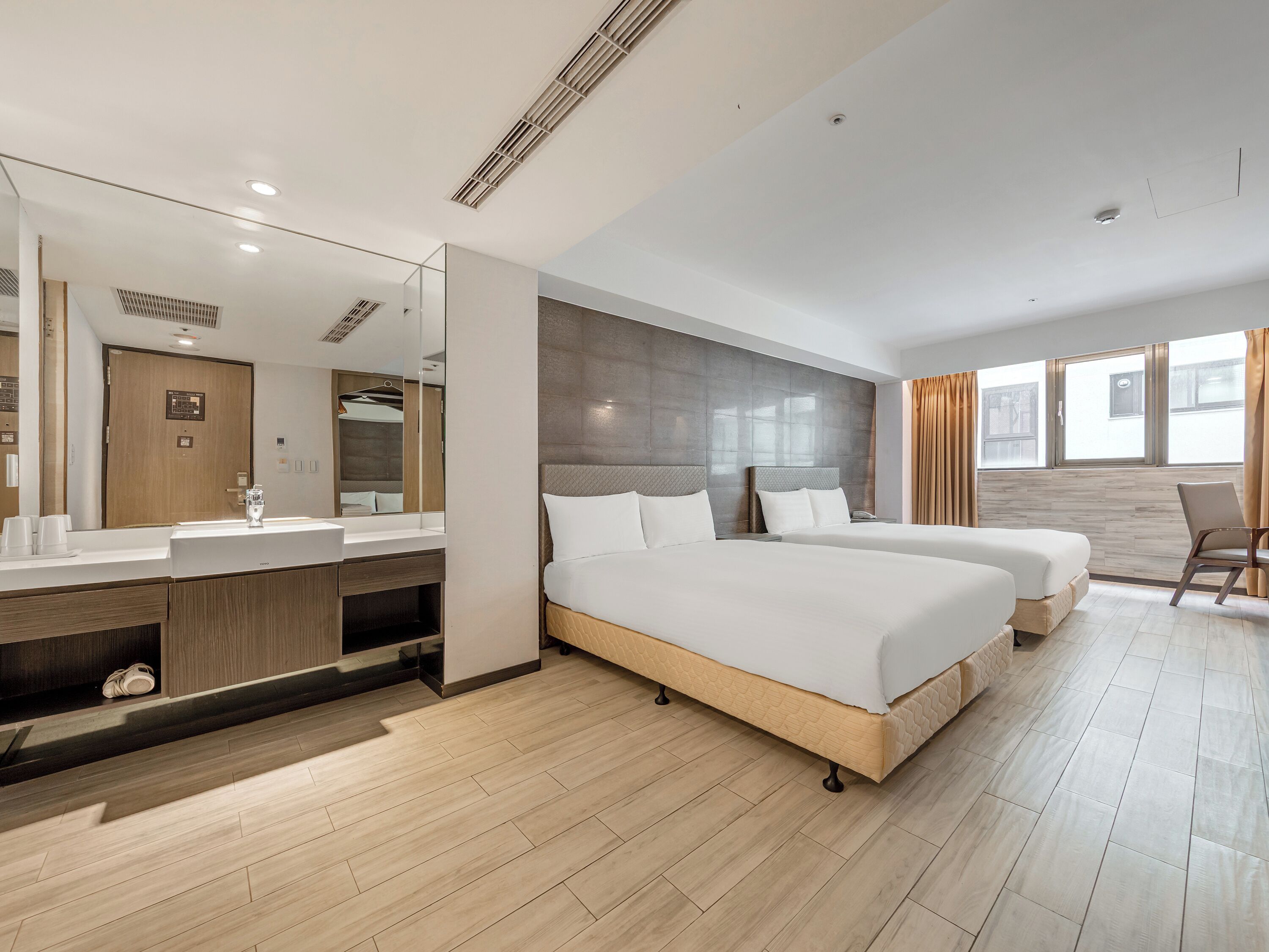 Une chambre d’hôtel dotée d’un grand lit, d’un coin salon séparé, d’une salle de bain avec un miroir et un lavabo, et offrant une vue par la fenêtre.