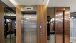 An elevator with a digital display, a wheelchair accessibility button, and a wooden panel design. - Guide Hotel Taipei Fuxing N (Taipei)