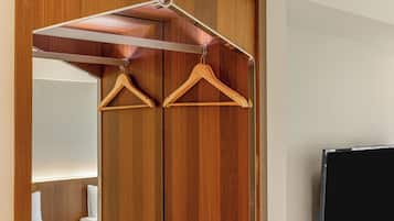 A hotel room with a wooden wardrobe, a mirror, and a television.