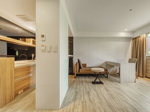 A modern hotel room with a kitchenette, a seating area with a table, and a view of the outdoors. - Guide Hotel Taipei Fuxing N (Taipei)