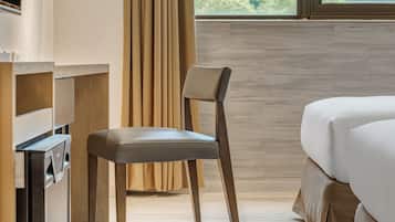Une chambre d’hôtel avec un lit, une chaise, un bureau et une fenêtre avec des rideaux.