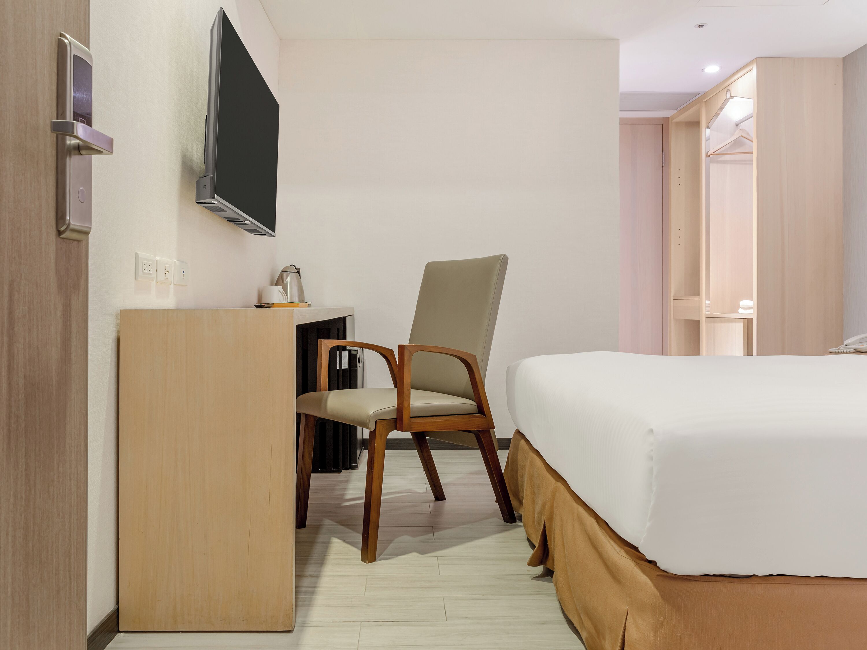 Ett hotellrum med en säng, ett skrivbord, en stol, en tv och en garderob.