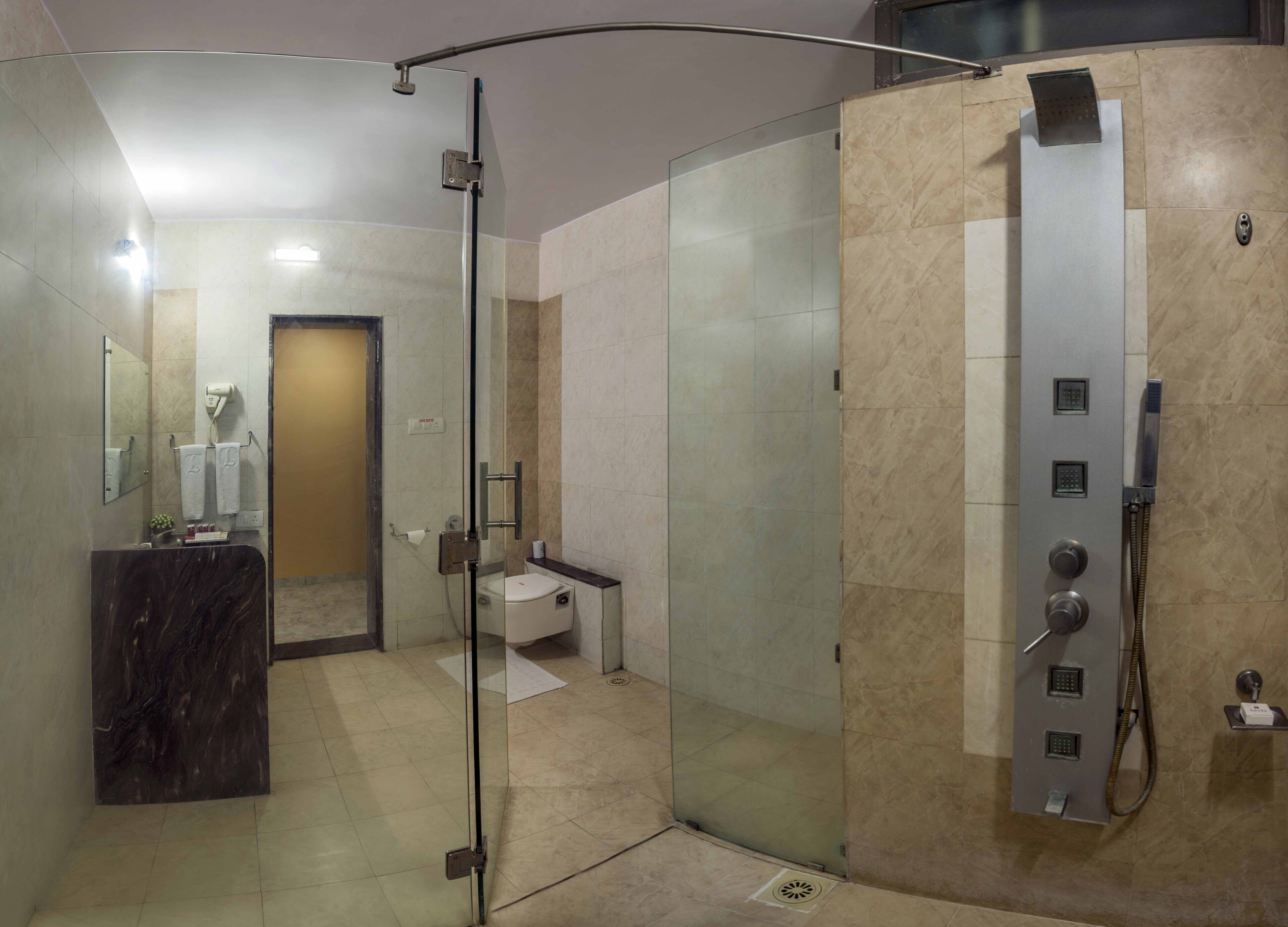 Ein modernes Badezimmer mit einer gläsernen Dusche, einem Marmorwaschtisch und einer Toilette.