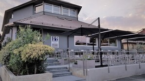 Een hotel met een terras, zitplaatsen buiten en een trap naar de ingang.