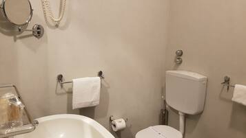 A bathroom with a toilet, sink, and a mirror.