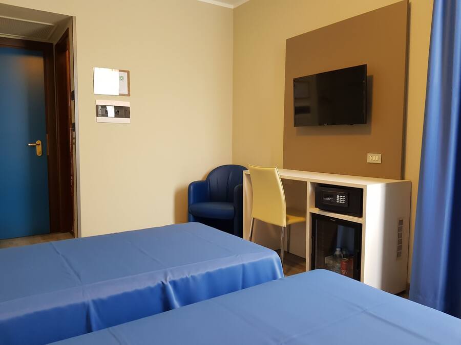 Habitación de hotel con dos camas, un escritorio, una silla, un televisor y un minibar.