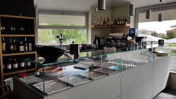 A modern bar area with a glass display case, shelves of liquor bottles, and a coffee machine.