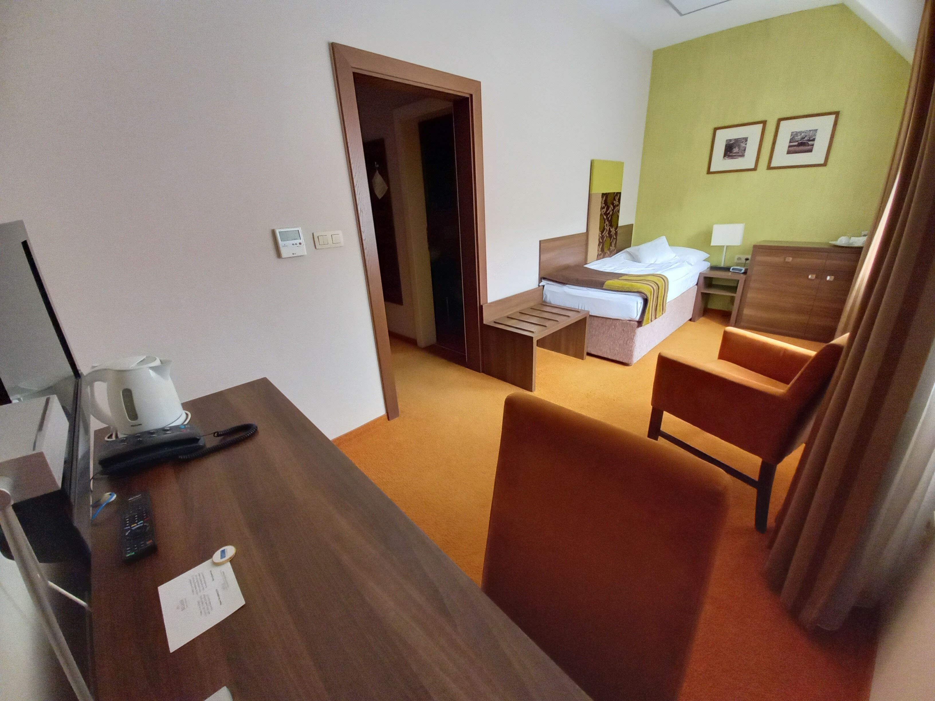 Une chambre d’hôtel avec un bureau en bois, un lit, une chaise et une petite table.