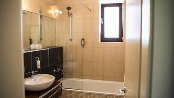 Un bagno moderno con vasca, doccia, lavandino e specchio.