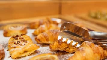 Una bandeja con varios pasteles, incluyendo croissants y un rollo de canela, servidos con una espátula.