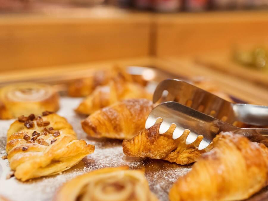 Una bandeja con varios pasteles, incluyendo croissants y un rollo de canela, servidos con una espátula.