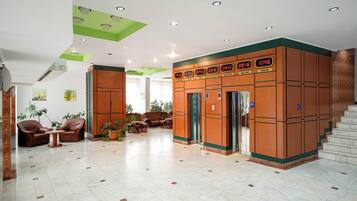 A lobby with a seating area, a staircase, and a wall with a digital clock displaying times in various cities.
