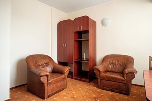 A room with two leather armchairs, a wooden cabinet, and a patterned carpet. - Egreta (Tulcea)