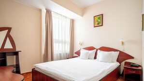 A hotel room with a bed, a desk, a chair, a nightstand, a lamp, and a painting on the wall. - Egreta (Tulcea)
