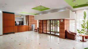 A hotel reception area with a reception desk, a seating area with a sofa and chairs, and a large glass door leading outside. - Egreta (Tulcea)