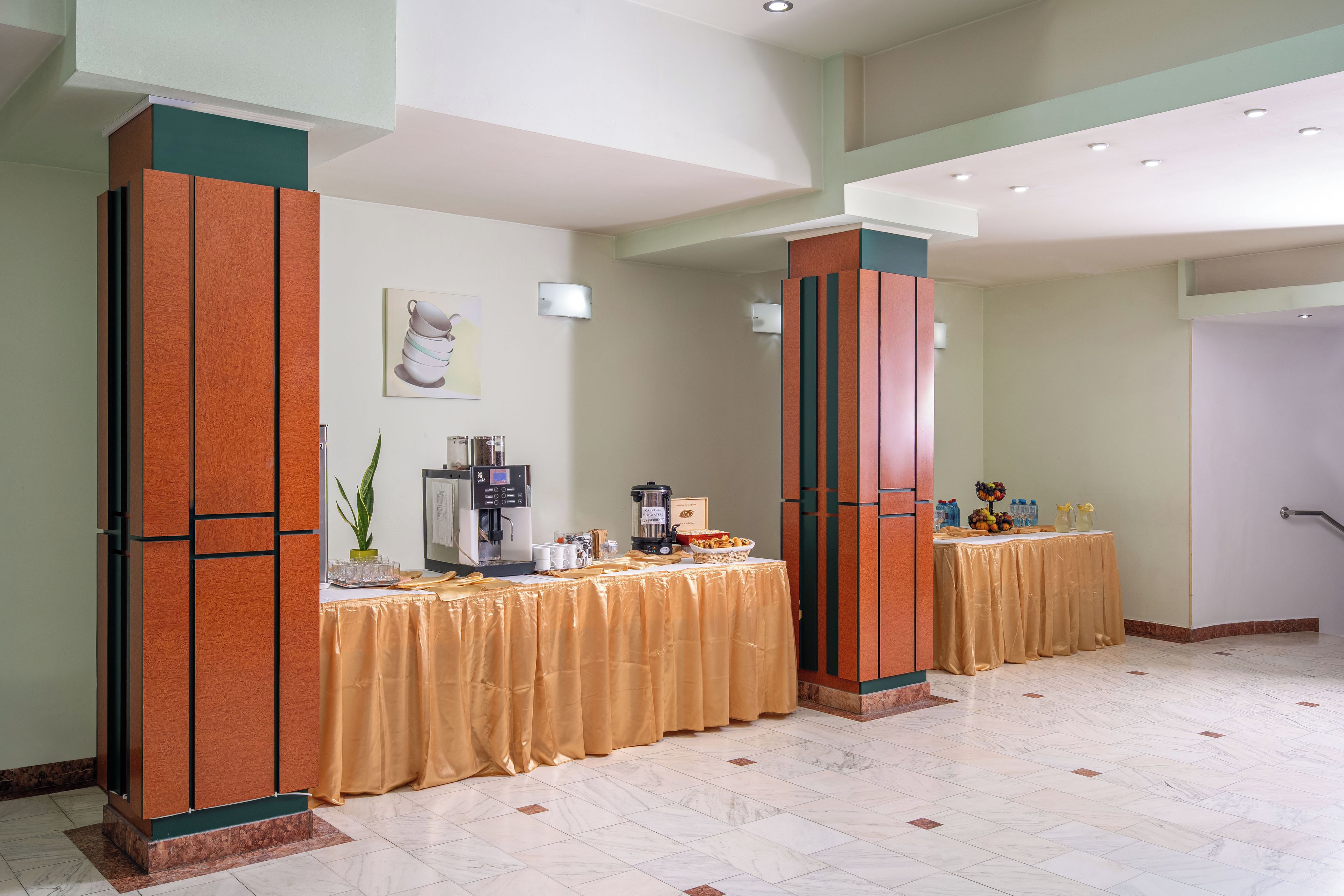 Un vestíbulo de hotel con mostrador de recepción, una máquina de café y una mesa de buffet.