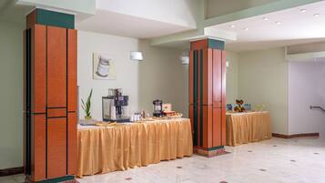 Un vestíbulo de hotel con mostrador de recepción, una máquina de café y una mesa de buffet.
