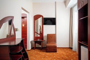 A hotel room with a wooden desk, a small side table, a single chair, a television mounted on the wall, and a wardrobe. - Egreta (Tulcea)