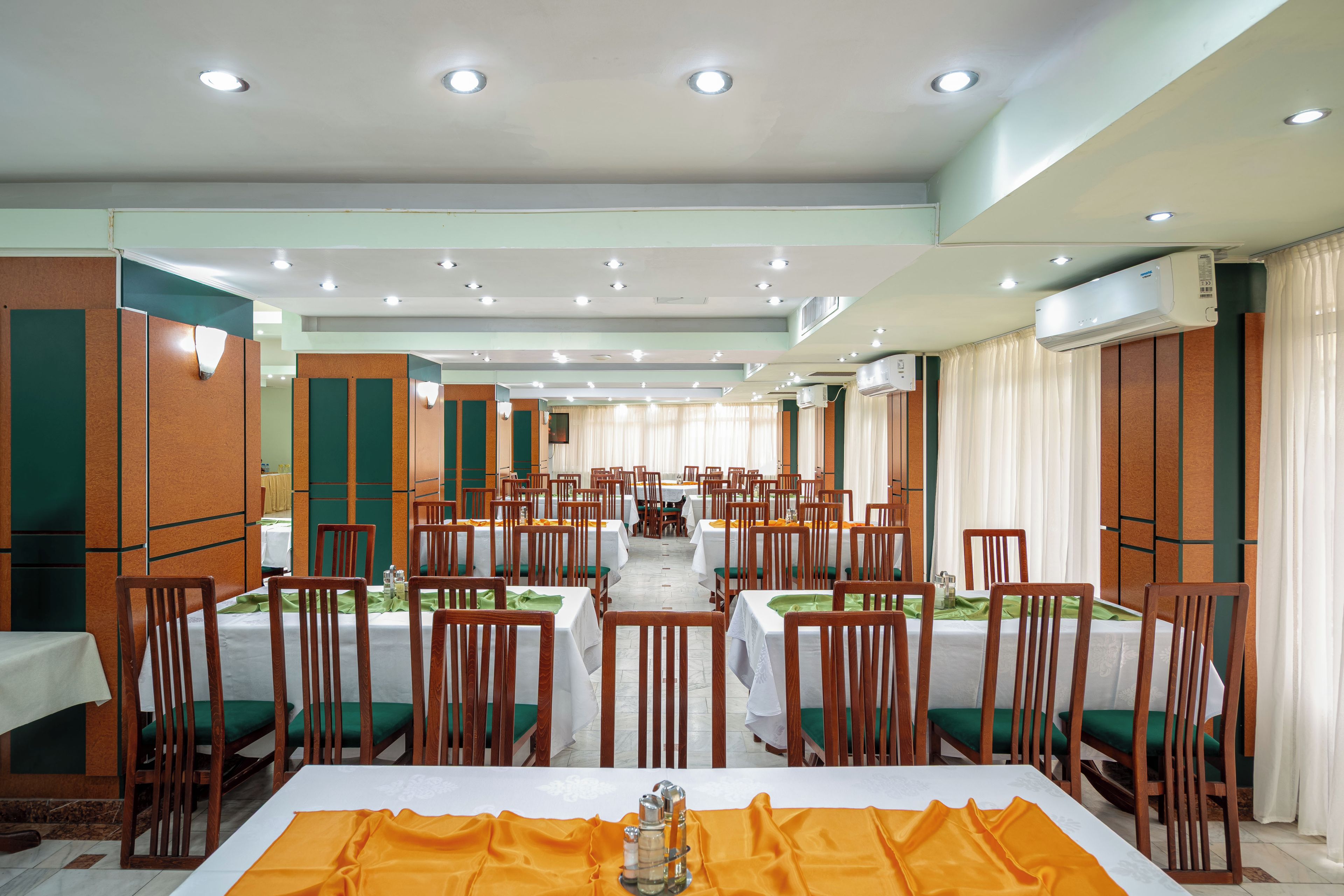 A hotel dining area with multiple tables and chairs, arranged in rows.