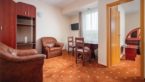 A room with a wooden cabinet, leather armchair, dining table with chairs, and a television on the wall. - Egreta (Tulcea)