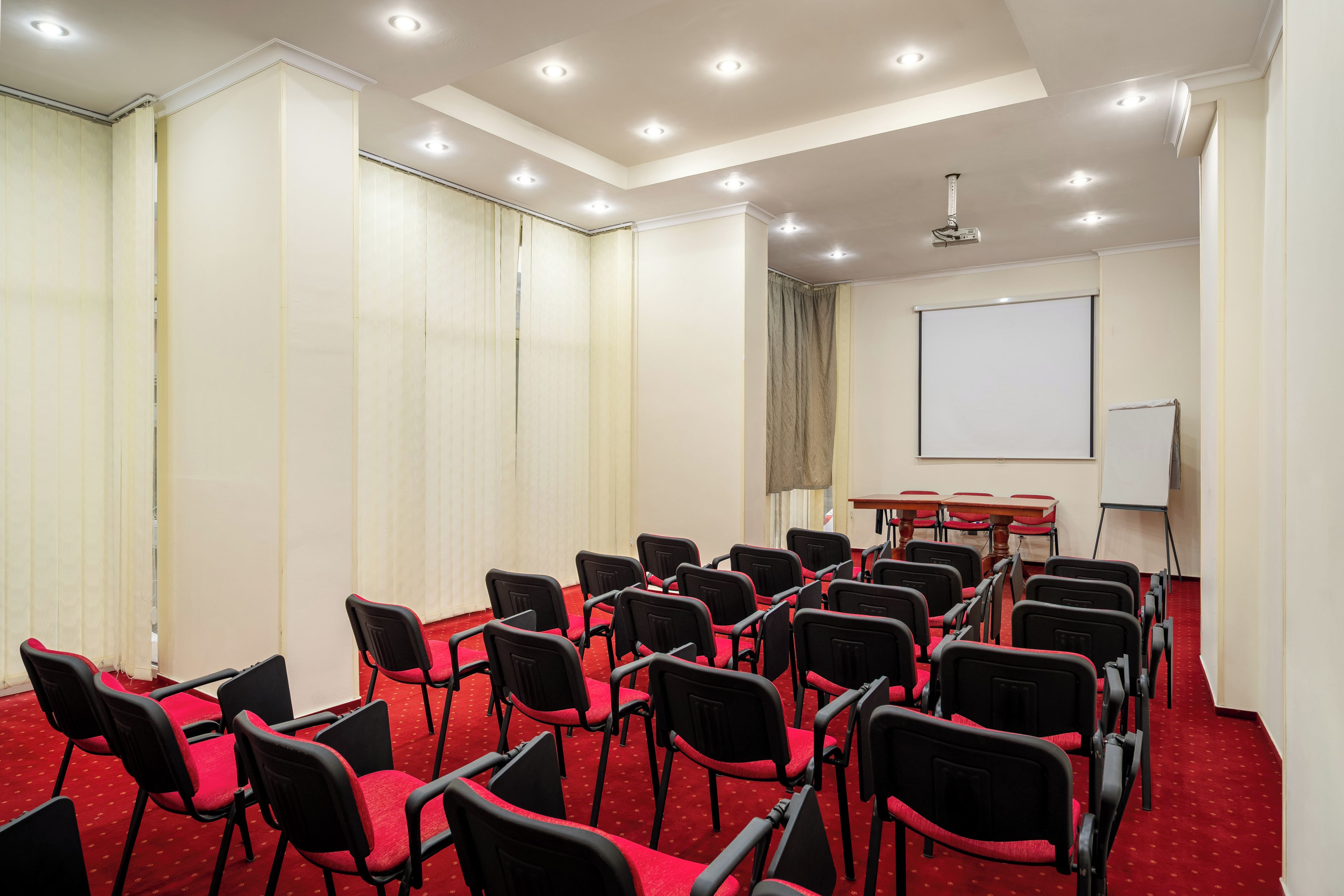 A conference room with rows of chairs, a projector screen, and a whiteboard.
