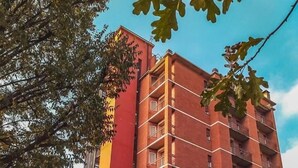 Un edificio de varios pisos con fachada roja, balcones y cielo despejado.