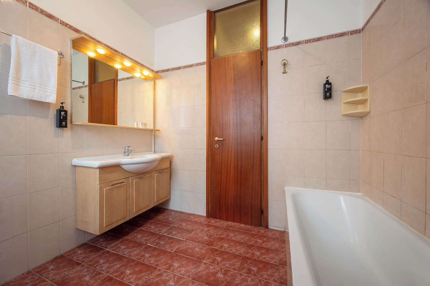 A bathroom with a sink, mirror, vanity, and a bathtub.