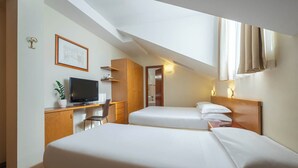 Una habitación de hotel con dos camas, un escritorio, un televisor y una planta pequeña.