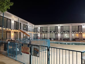 A multi-story hotel with a swimming pool, outdoor seating, and a lifeguard duty warning sign. - Ozark Valley Lodge (Branson)