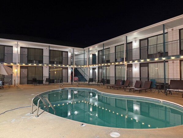 A hotel with a swimming pool, outdoor seating, and a covered area with string lights. - Ozark Valley Lodge (Branson)
