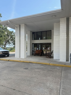 A building with a covered entrance, large windows, and outdoor seating. - Ozark Valley Lodge (Branson)