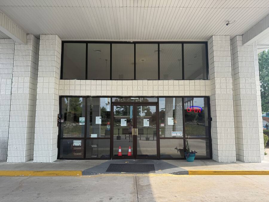 Entrada de un edificio con puerta de cristal, un cartel que dice 'Breakfast Room' y un letrero de 'No Parking'.