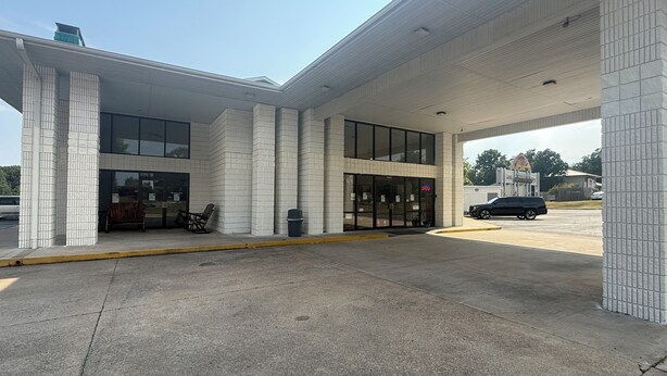 A gas station with a paved entrance, a trash bin, and a bench outside. - Ozark Valley Lodge (Branson)