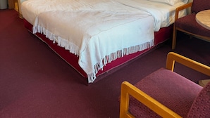 A hotel room with a bed, a nightstand, a lamp, a chair, and two wall art pieces. - Ozark Valley Lodge (Branson)