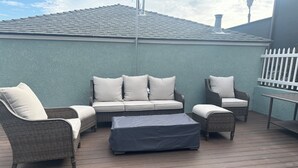 An outdoor patio with wicker furniture, including a sofa and chairs, and a small table. - The Palomar Inn (Pismo Beach)