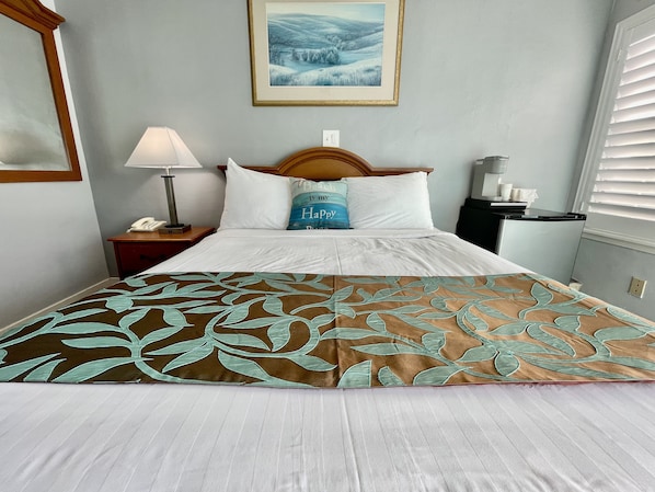 Cozy retreat with a neatly made bed, bedside table, and a beautiful framed landscape painting.