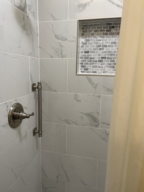 Experience a sleek and contemporary shower area with a large tile wall, small window, and functional shower door.
