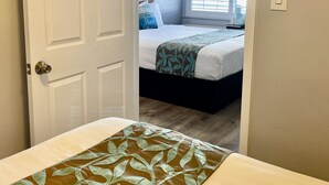A bedroom with a bed, a window, and a door. - The Palomar Inn (Pismo Beach)