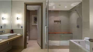 Un baño moderno con ducha de mampara de vidrio, un espejo grande y una bañera independiente.