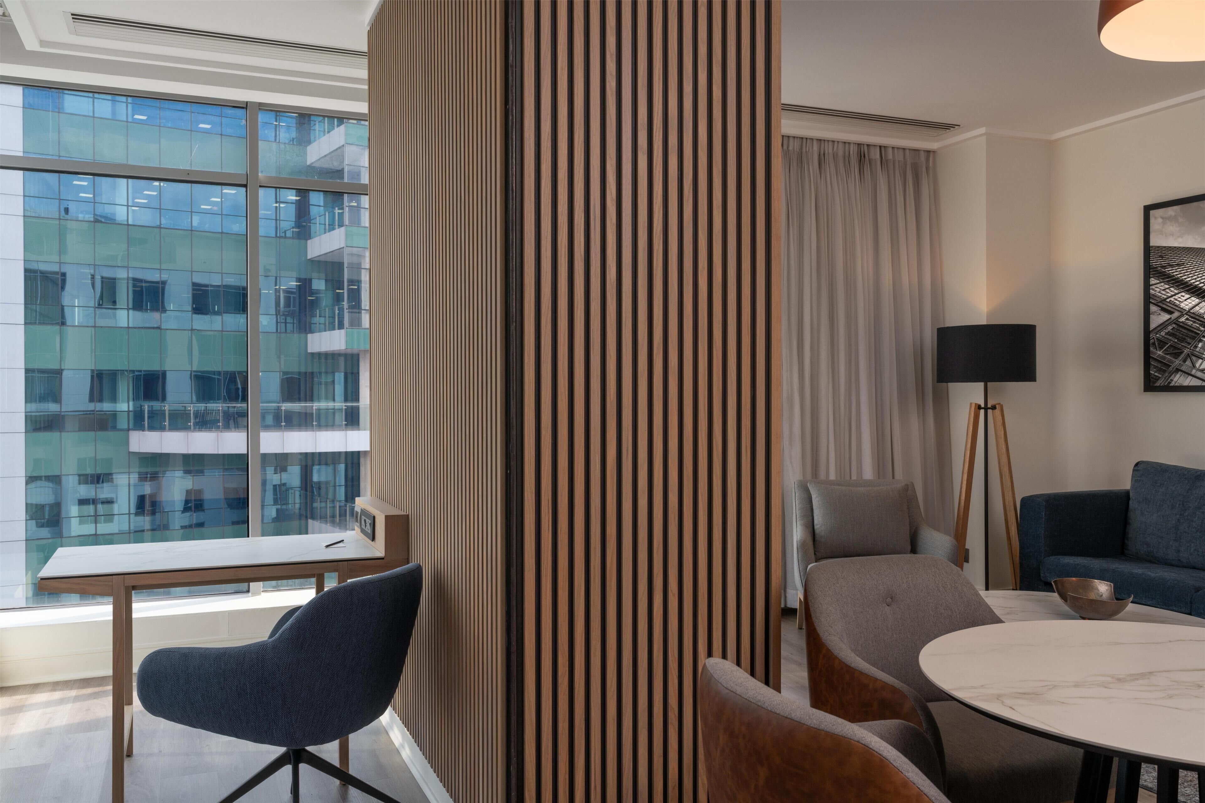 Quarto de hotel moderno com uma janela grande, uma mesa redonda e duas cadeiras.