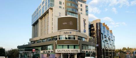A hotel with a prominent sign for the Gautrain Hotel, featuring a modern design with multiple floors and large windows.