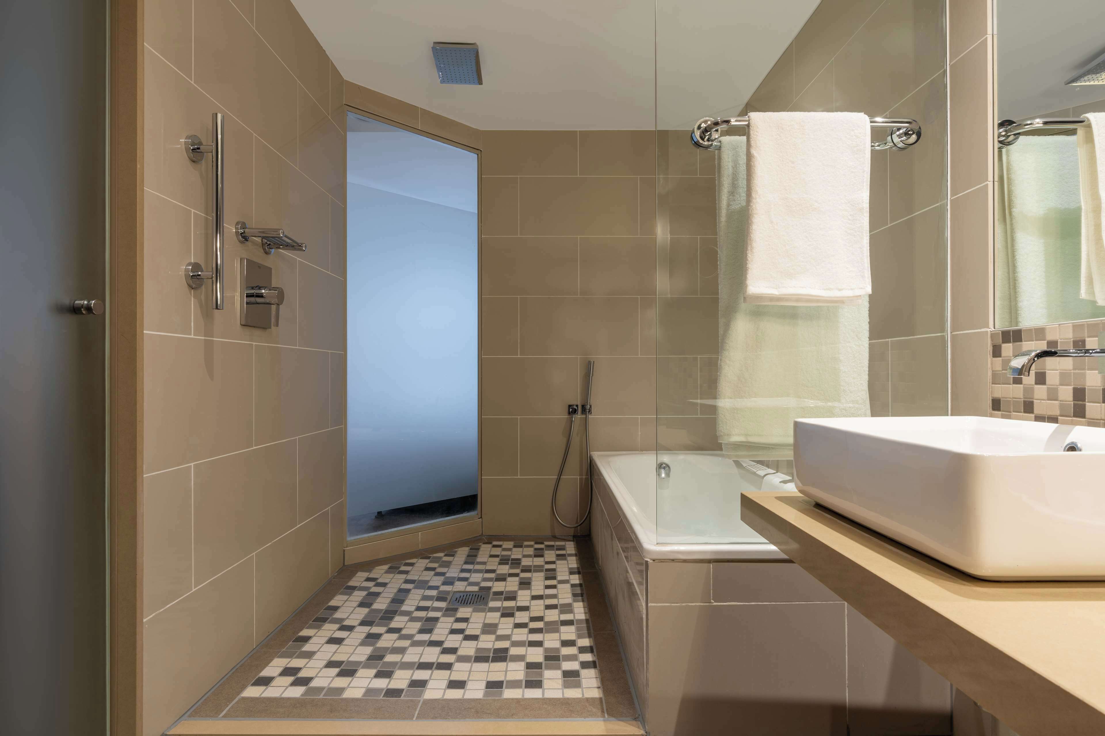 A modern bathroom with a shower, a bathtub, and a sink.