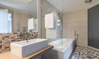 Un baño moderno con un espejo grande, un lavamanos blanco y una bañera.