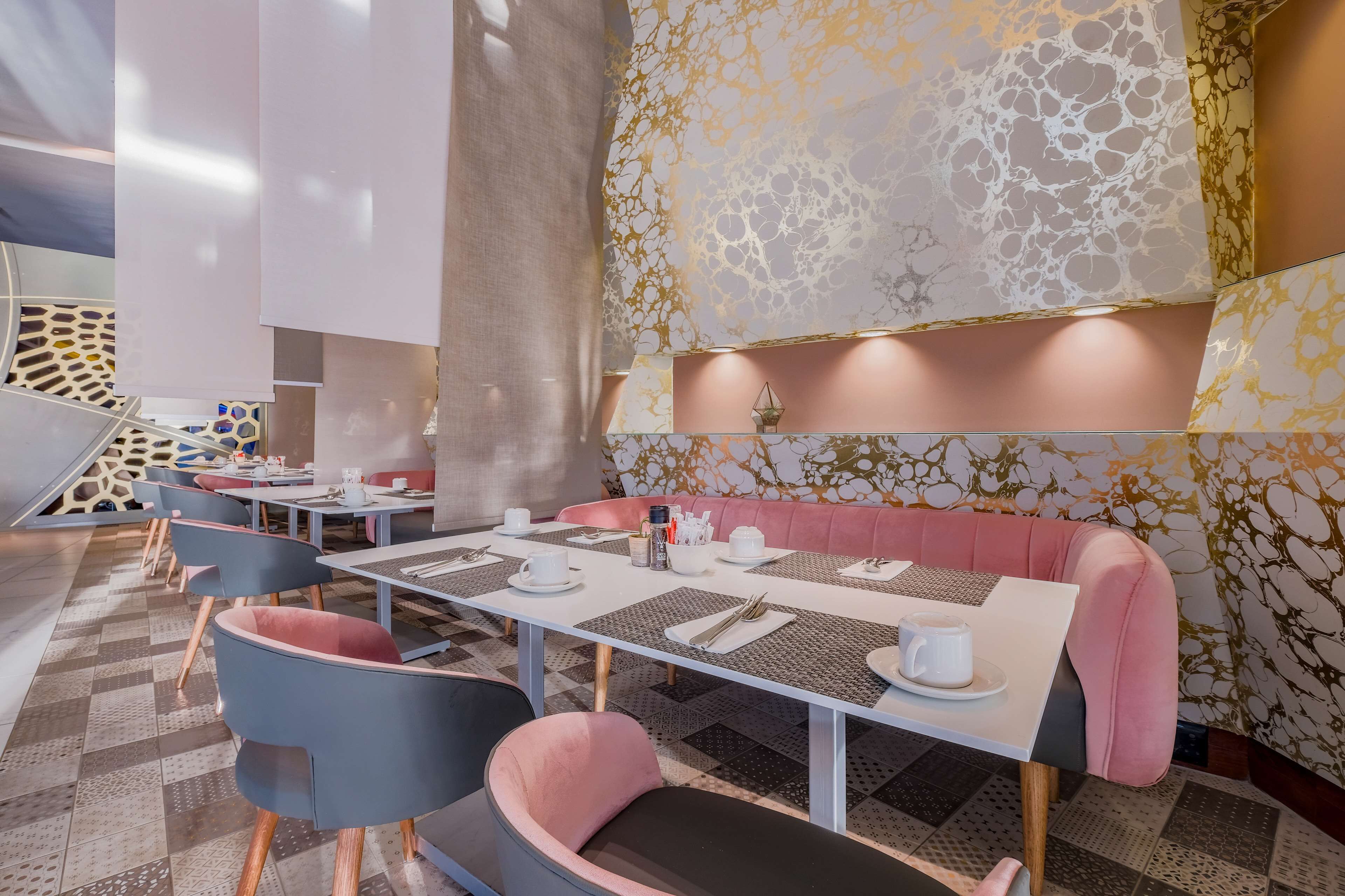 Een moderne eethoek met tafels, stoelen en een roze zitgedeelte.