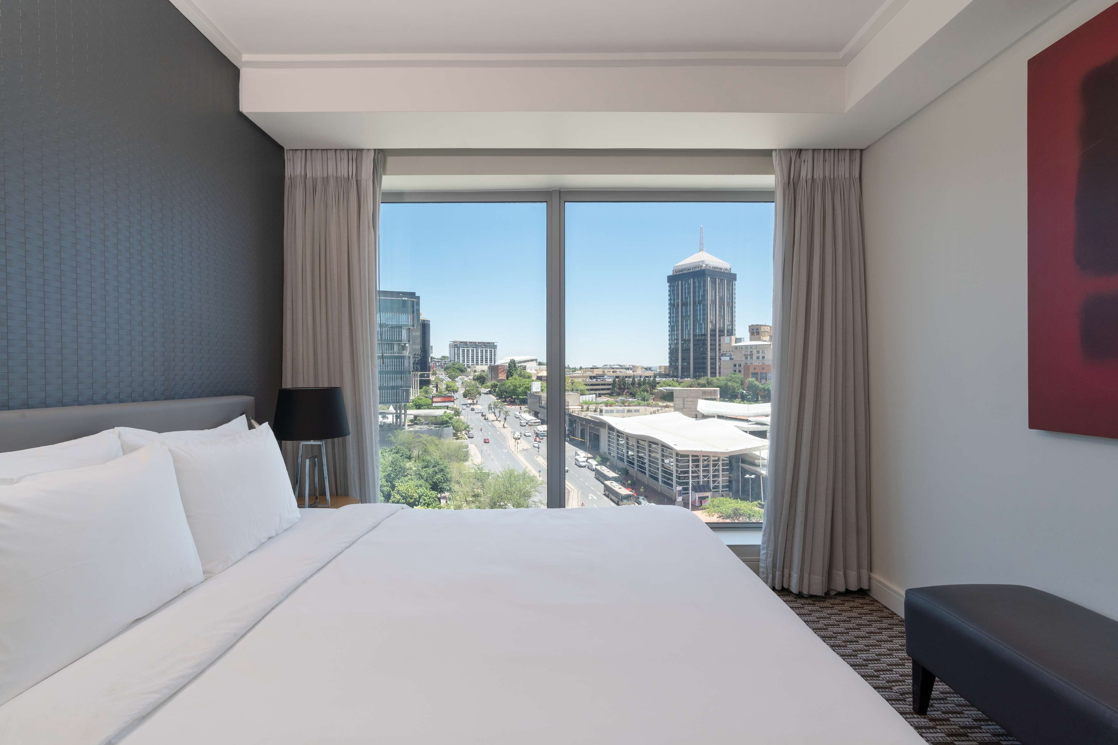 A hotel room with a large bed, a view of the city, and a modern design.