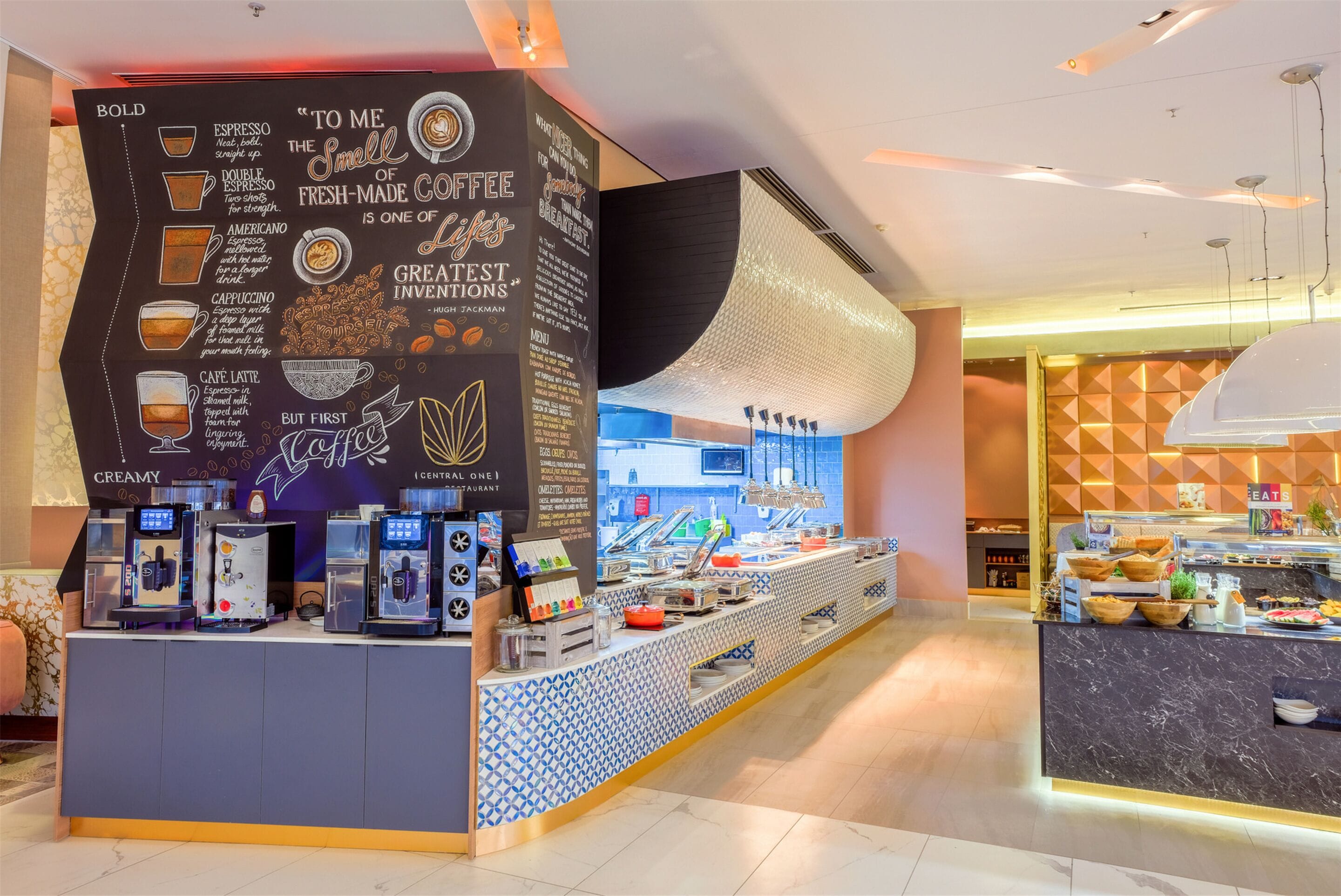 A coffee station with espresso machines, a menu board, and a counter with food items.