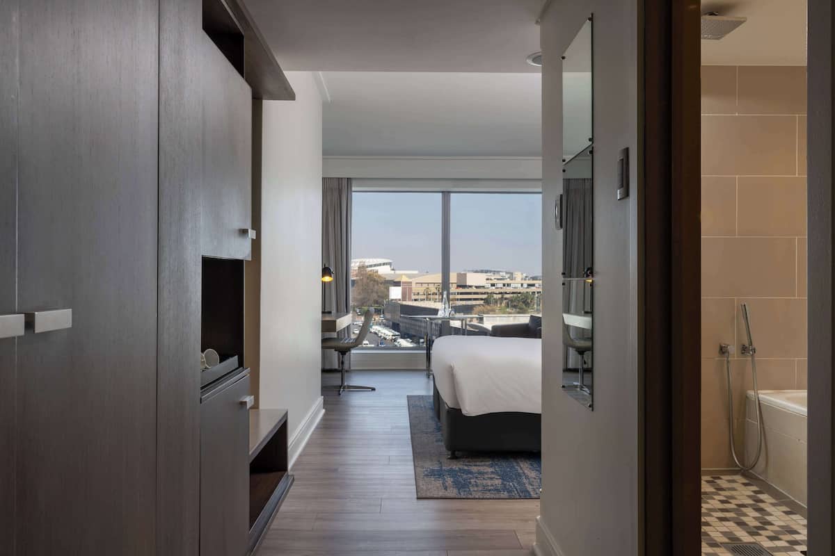 Une chambre d’hôtel moderne avec un grand lit, un bureau et une vue sur la ville.