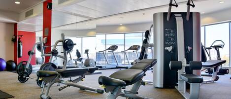 A gym with exercise equipment, treadmills, and a large window.