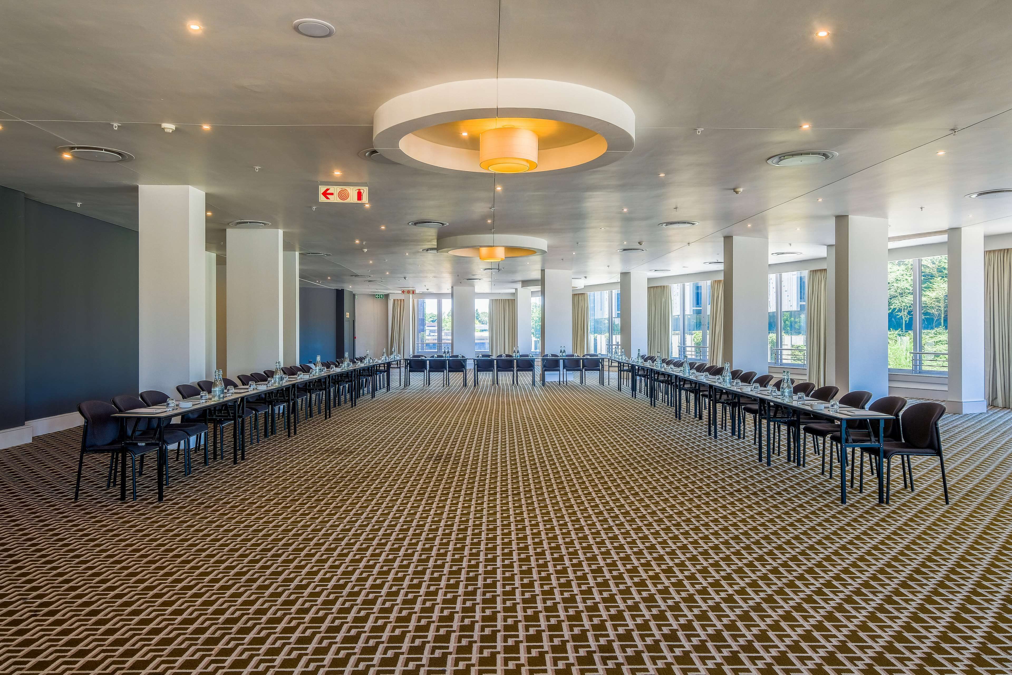 A conference room with a long table, chairs, and a patterned carpet.